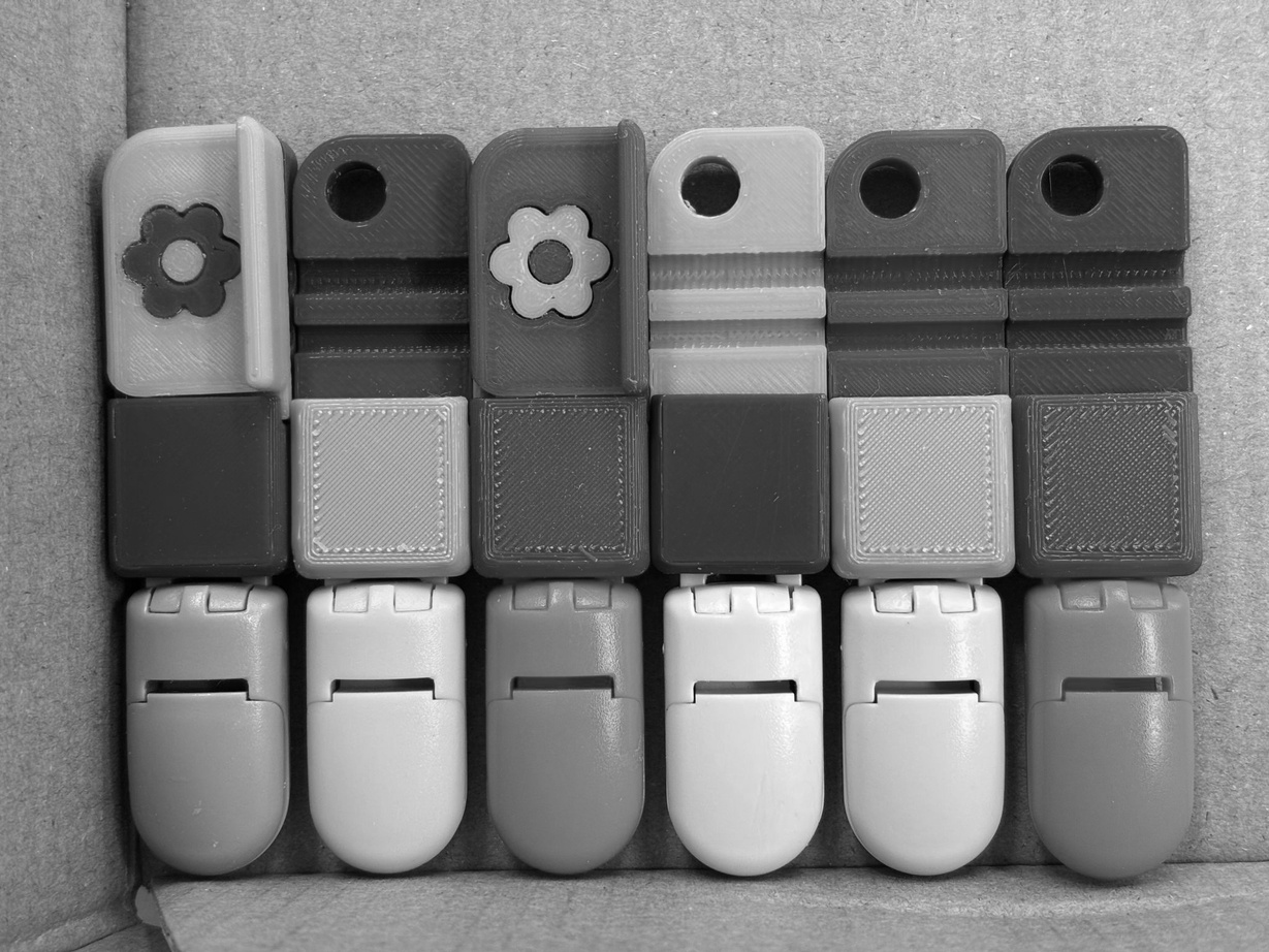 Six 3D-printed prototype iterations of the clamp, laid out in a row